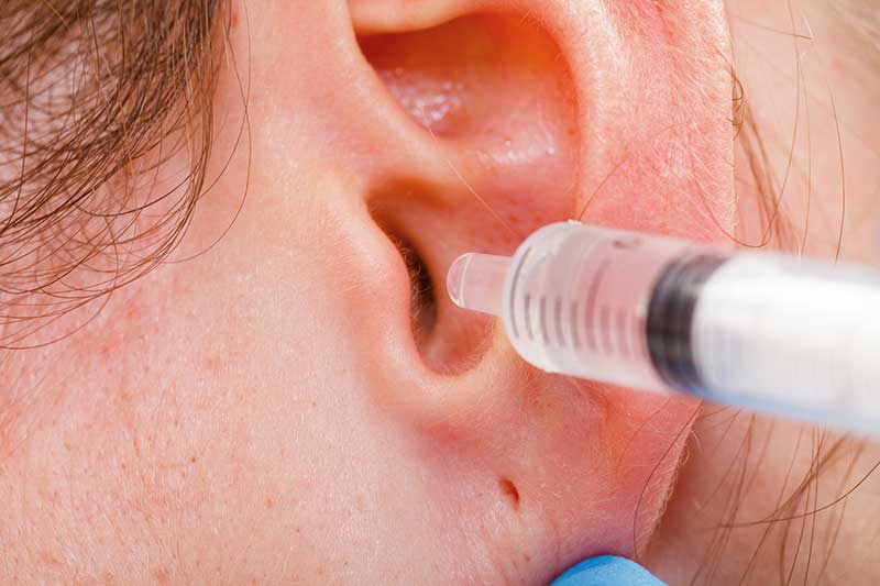 closeup of a patient's ear being irrigated to remove earwax
